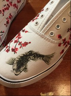 50+ Easy DIY Crafts to Sell and Make Extra Money Easy DIY crafts to sell: A white canvas shoe hand-painted with a detailed black and grey koi fish on the toe and surrounded by delicate red cherry blossom branches.