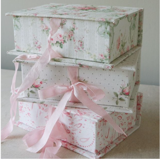50+ Easy DIY Crafts to Sell and Make Extra Money Easy DIY crafts to sell: A stack of three fabric-covered storage boxes featuring vintage pink floral and dotted patterns, each tied with a delicate pink satin ribbon bow.