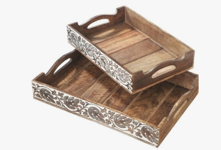 50+ Easy DIY Crafts to Sell and Make Extra Money Easy DIY crafts to sell: Two nested wooden serving trays with cutout handles and hand-carved white floral patterns along the outer sides.