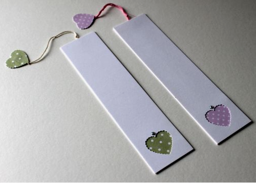 50+ Easy DIY Crafts to Sell and Make Extra Money Easy DIY crafts to sell: Two white paper bookmarks, each featuring a cut-out heart near the bottom revealing patterned polka-dot paper underneath, and a matching string tied at the top with a small dangling paper heart.