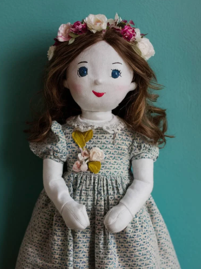 50+ Easy DIY Crafts to Sell and Make Extra Money Easy DIY crafts to sell: A handmade rag doll with yarn hair and a hand-stitched face, wearing a green polka-dot dress with lace trim and a pink bow, surrounded by delicate lace fabric and pink decorative roses.