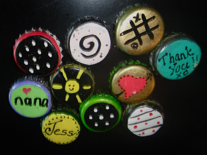 50+ Easy DIY Crafts to Sell and Make Extra Money Easy DIY crafts to sell: A collection of handmade bottle cap magnets painted with various designs, including text like "Nana" and "Jess", a red heart, polka dots, a smiley sun, and a hashtag symbol.