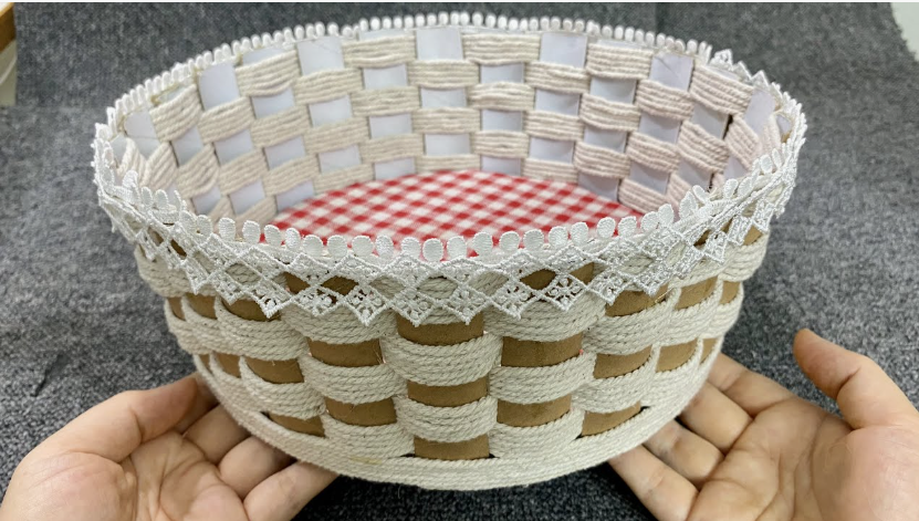 50+ Easy DIY Crafts to Sell and Make Extra Money Easy DIY crafts to sell: A handmade woven basket held in two hands, featuring a red and white checkered inner lining, natural twine-wrapped strips, and a delicate white lace trim along the upper edge.