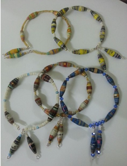 50+ Easy DIY Crafts to Sell and Make Extra Money Easy DIY crafts to sell: A selection of handmade beaded necklaces and bracelets featuring colorful paper-rolled beads in shades of yellow, white, brown, and blue, accented with matching glass beads and dangling charms.