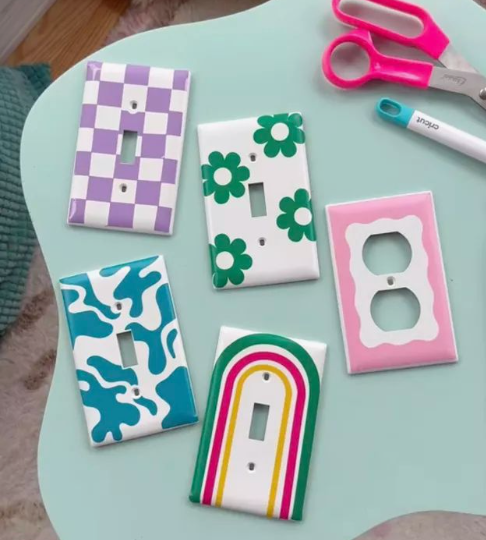 50+ Easy DIY Crafts to Sell and Make Extra Money DIY crafts to sell: colorful painted light switch covers featuring trendy checkerboard, floral, and rainbow patterns.