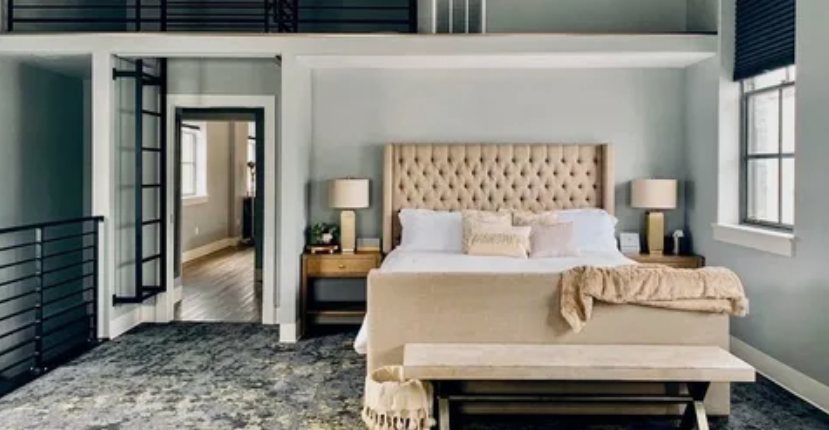 Small Living Room Decor Ideas on a Budget: 25 Stylish Ways to Make It Look Expensive Modern bedroom featuring small living room decor ideas on a budget with a large tufted beige upholstered bed, matching wooden nightstands with lamps, a bench at the foot of the bed, and a loft overlook with metal railings.