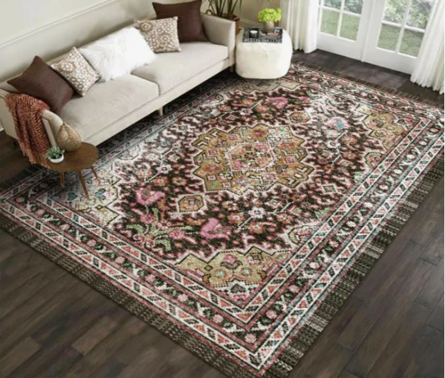 Small Living Room Decor Ideas on a Budget: 25 Stylish Ways to Make It Look Expensive Living room featuring small living room decor ideas on a budget with a light beige sofa with various accent pillows, a dark ornate traditional area rug, a small side table, a white footstool, and dark wood flooring.