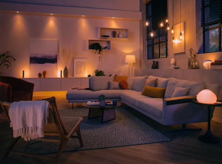 Small Living Room Decor Ideas on a Budget: 25 Stylish Ways to Make It Look Expensive Warmly lit modern living room featuring small living room decor ideas on a budget with a large sectional sofa, ambient recessed and pendant lighting, floating wall shelves, a coffee table, and an accent armchair.