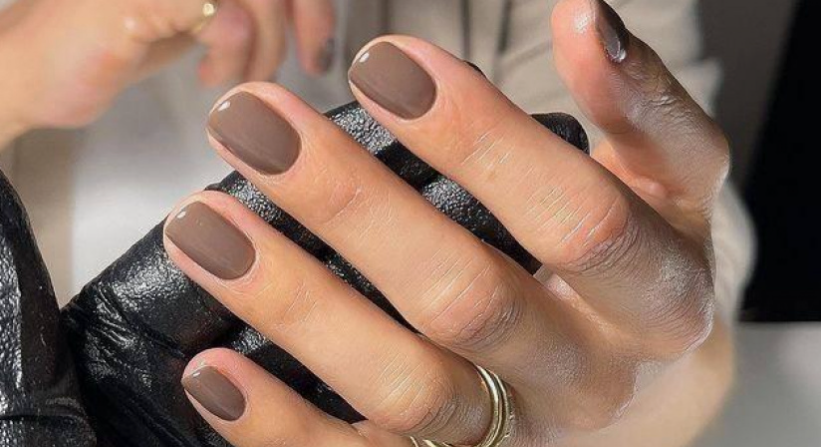 Short nail designs featuring glossy, neutral brown polish on neatly manicured square nails.