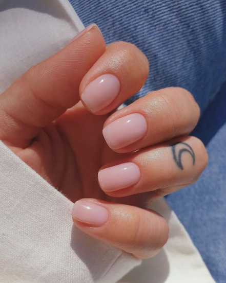 Short nail designs featuring glossy, translucent pale pink polish on clean, short square nails.