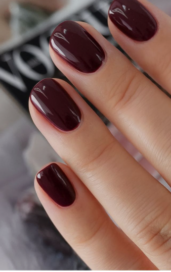 Short nail designs featuring high-gloss, deep dark burgundy or maroon polish on cleanly groomed short nails.