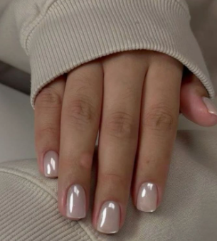 Short nail designs featuring glossy, neutral nude polish with a shimmering chrome finish on short square nails.
