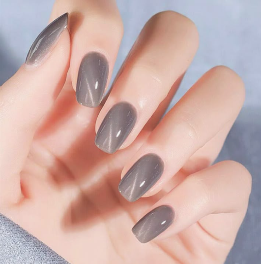 Short nail designs featuring glossy grey cat-eye polish with a shimmering reflective center streak on neatly rounded short nails.