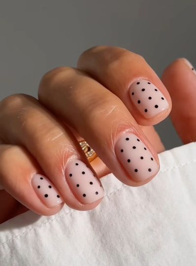 Short nail designs featuring playful black polka dots neatly spaced on a neutral glossy base.