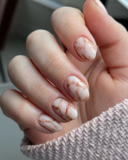 Short nail designs featuring an elegant brown and white marble stone effect on glossy, rounded short nails.