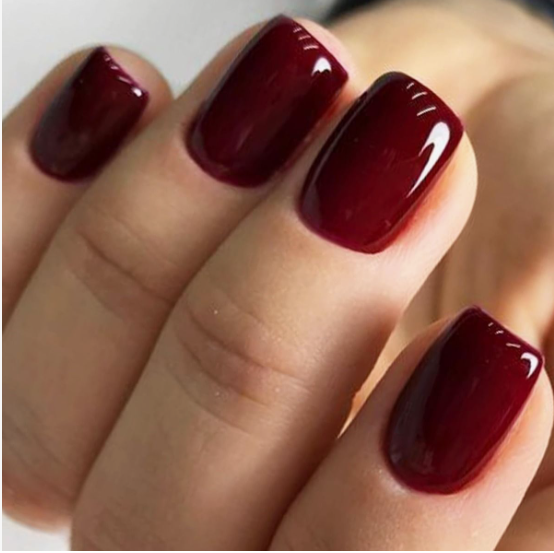 Short nail designs featuring glossy deep burgundy or wine-red polish on clean, short square nails.