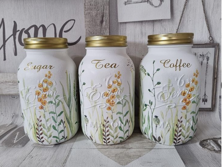 Three white painted mason jars labeled for sugar, tea, and coffee with delicate floral designs, showcasing beautiful DIY crafts using things you have at home.