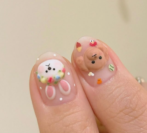 15 Stunning 3D Nail Designs to Try This Season Cute 3D nail designs featuring an adorable brown teddy bear and a white cartoon character surrounded by pastel details.
