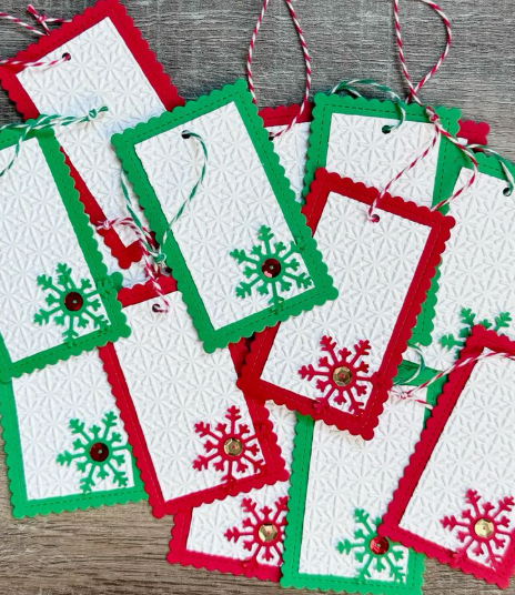 A collection of handmade Christmas gift tags featuring embossed white cardstock, scalloped red and green borders, and snowflake cutouts for DIY crafts using things you have at home.
