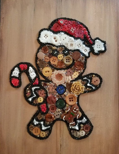 A mosaic gingerbread man figure completely covered in various buttons and beads wearing a Santa hat for DIY crafts using things you have at home.