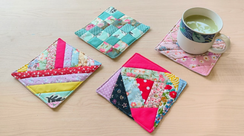 A collection of colorful quilted fabric coasters arranged on a wooden table, featuring geometric patchwork designs for DIY crafts using things you have at home.