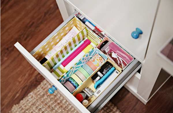 A neatly organized desk drawer fitted with custom dividers made from patterned cardboard boxes for DIY crafts using things you have at home.