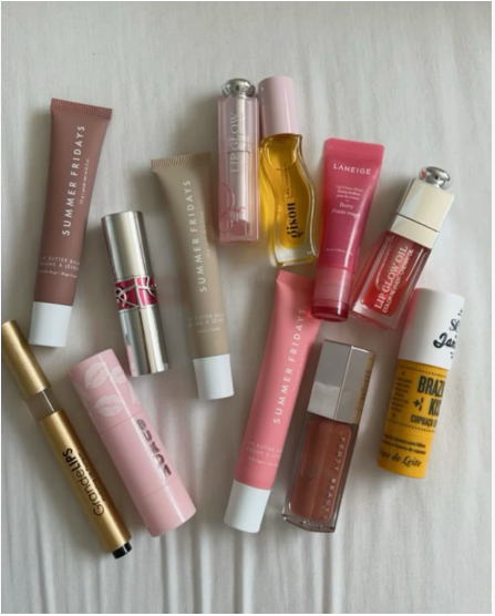 The Minimal Makeup Guide: How to Look Polished With Less Makeup A collection of various branded lip balms, glosses, and oils, including Summer Fridays, Laneige, and Fenty Beauty, arranged on a light surface.