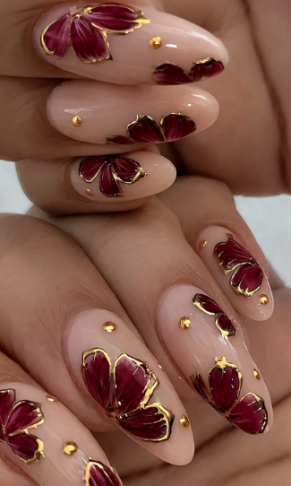 15 Stunning 3D Nail Designs to Try This Season Elegant 3D nail designs showcasing deep burgundy sculpted flowers outlined in metallic gold with tiny gold accent studs on a neutral base.