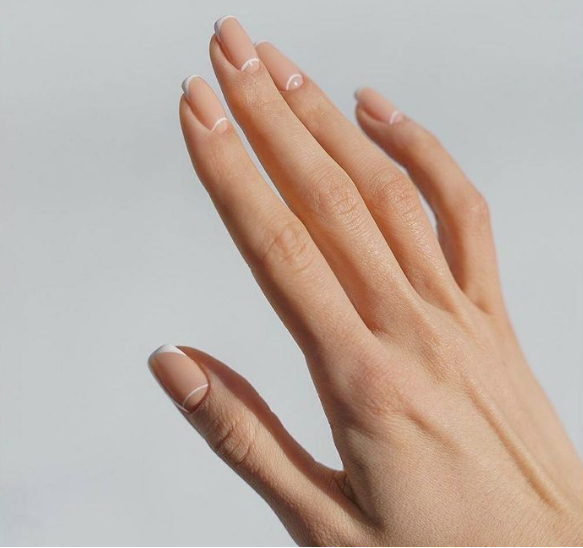 Neutral nude nails with subtle white micro-line accents showcasing low-maintenance nail designs.