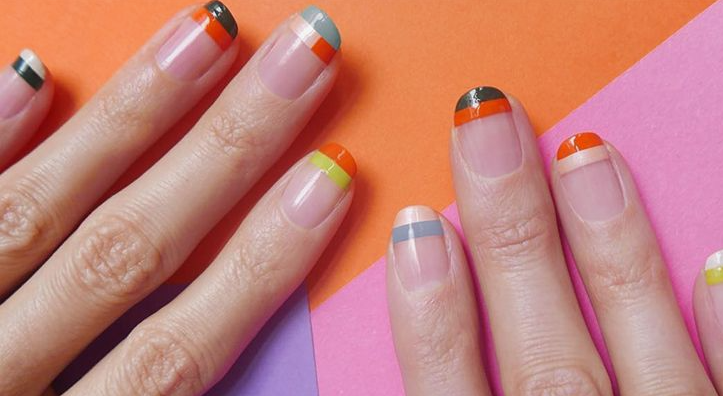 Modern geometric negative space manicure with colorful tip stripes showcasing low-maintenance nail designs.