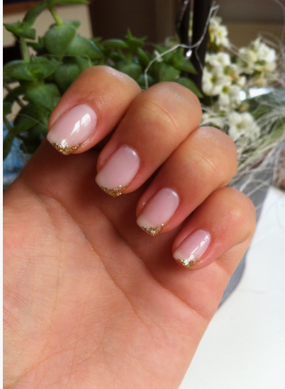 Short neutral pink nails featuring sparkly gold glitter tips showcasing low-maintenance nail designs.