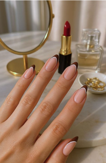 Glossy nude almond nails featuring dark brown French tips with thin white outline details showcasing low-maintenance nail designs.