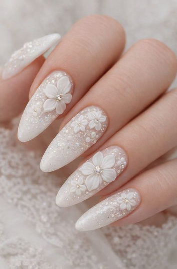 15 Stunning 3D Nail Designs to Try This Season Bridal-inspired 3D nail designs featuring intricate sculpted white flowers, tiny pearl accents, and sparkling glitter on an almond-shaped manicure.