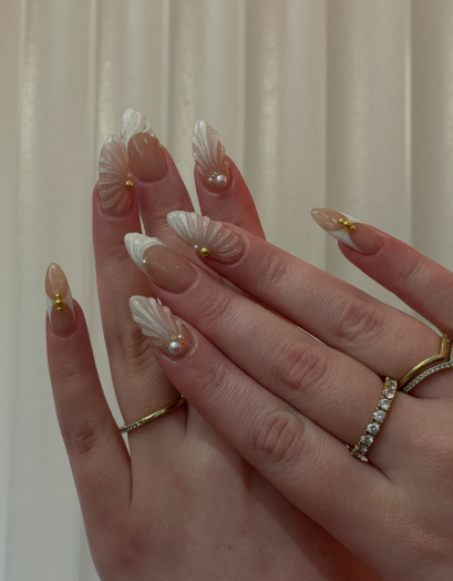 15 Stunning 3D Nail Designs to Try This Season Elegant 3D nail designs showcasing sculpted seashell and mermaid tail patterns accented with tiny pearls and gold beads on a nude and French tip base.