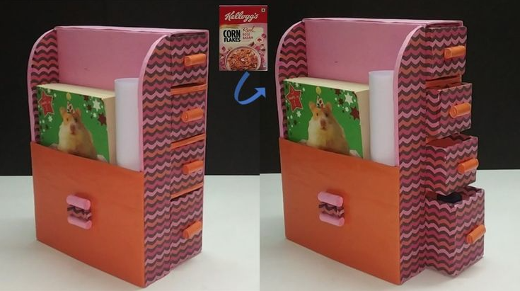 A desktop organizer crafted from recycled cardboard and cereal boxes featuring patterned paper, a large orange bottom drawer, and a stack of four smaller drawers.