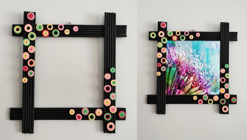 A black DIY picture frame crafted from rolled paper tubes, decorated with colorful paper quilling circles and holding a nature photograph.