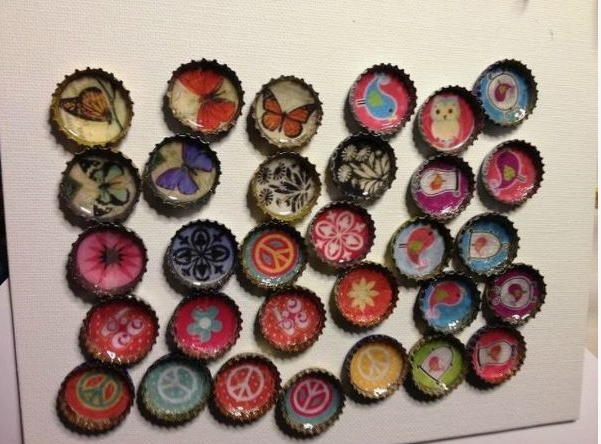 A collection of decorative bottle cap magnets featuring various colorful designs, including butterflies, birds, peace signs, and floral patterns as part of easy upcycling crafts for beginners.