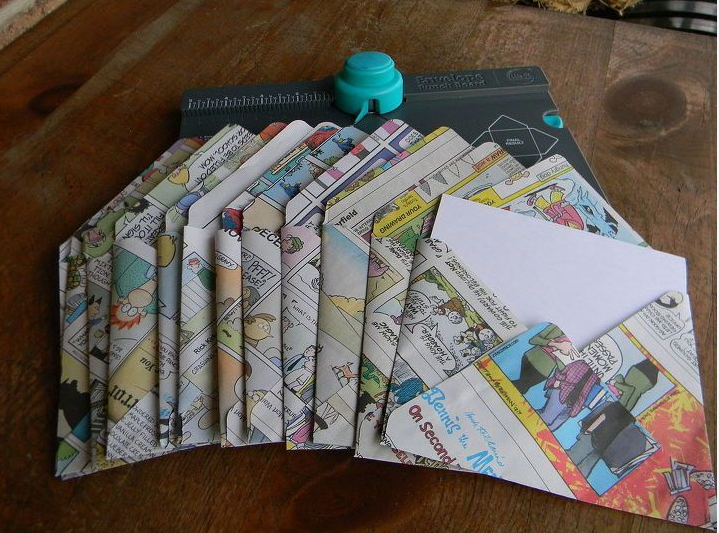 A set of colorful envelopes crafted from comic book pages, displayed alongside an envelope punch board.