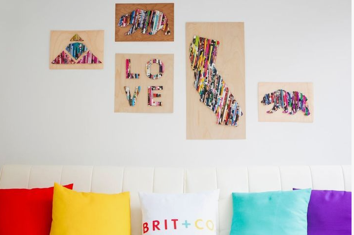 A wall arrangement featuring various wooden art pieces decorated with colorful rolled paper tubes, including shapes of a bear, the state of California, a diamond, and the word "LOVE".