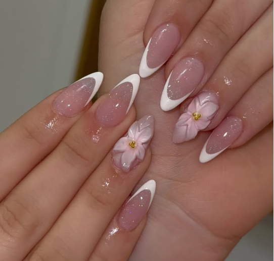 15 Stunning 3D Nail Designs to Try This Season Elegant 3D nail designs showcasing classic white French tips combined with sculpted pastel pink 3D floral accents featuring golden centers on a shimmering pink base.