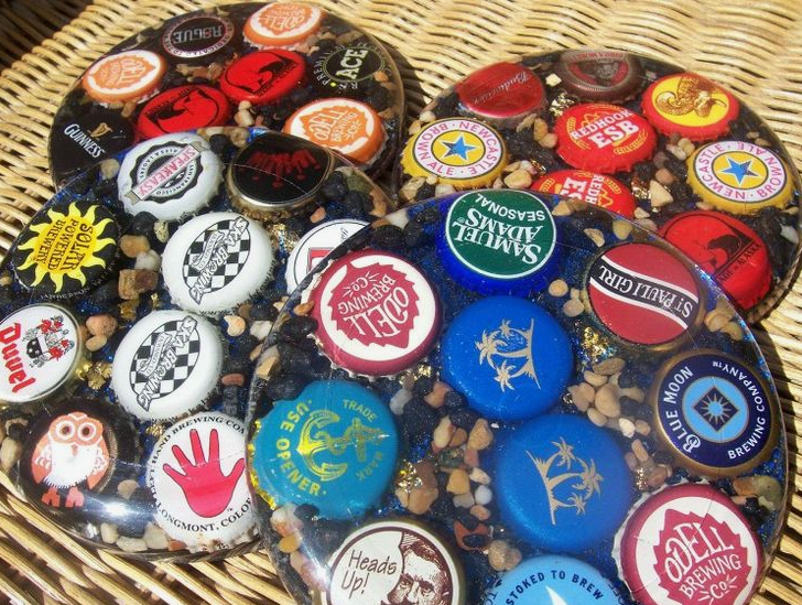 A collection of resin coasters embedded with colorful beer bottle caps and small pebbles.