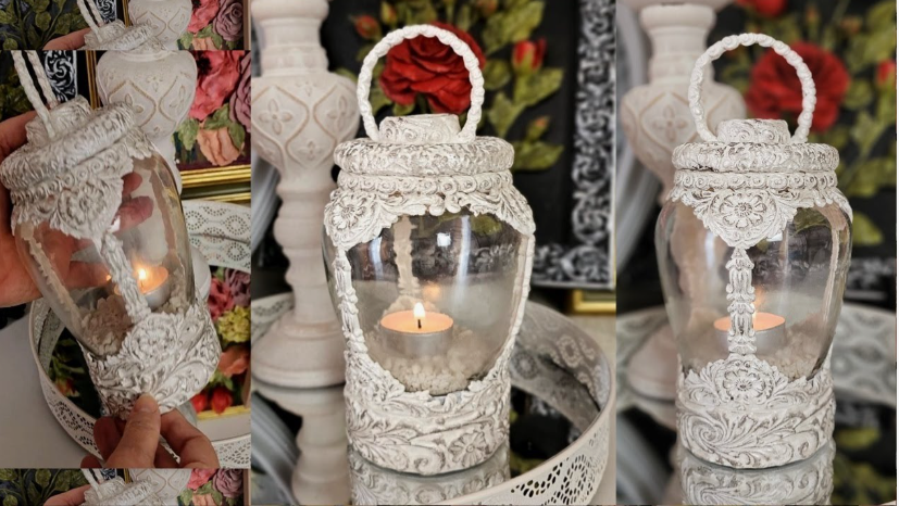 A DIY decorative candle lantern made from a glass jar embellished with ornate white molded patterns, distressed texturing, and a matching handle, holding a lit tealight candle.