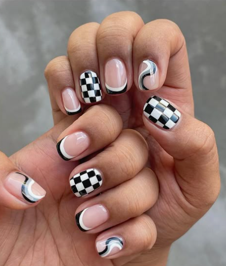Short, rounded nails featuring a mix of black-and-white checkerboard prints, minimalist black French tips, and abstract wavy lines, presenting creative easy nail designs for short nails.