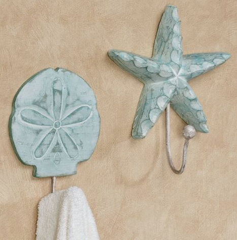 Two seafoam green ocean-themed wall hooks showcasing unique air dry clay ideas, shaped like a sand dollar and a starfish holding small towels.