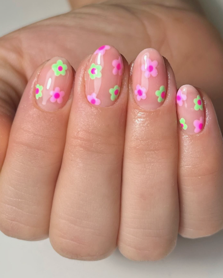 Short, rounded nails featuring a glossy translucent nude base decorated with vibrant pink and light green neon flower patterns, capturing a playful and easy nail design for short nails.