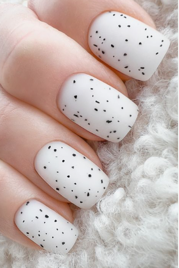 Short, square-cut nails featuring a matte white base speckled with tiny black flecks, mimicking a chic robin's egg or stone texture as an ideal option for easy nail designs for short nails.