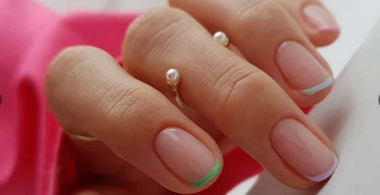Short, rounded nails featuring a clean nude base accented with delicate pastel-colored French tips in soft green, light blue, and pale pink, offering a sweet and simple option for easy nail designs for short nails.