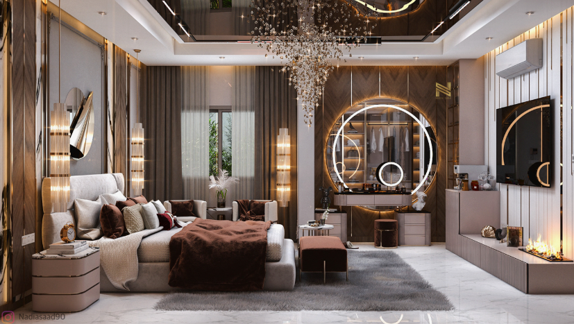 A luxurious and expansive bedroom featuring an upholstered bed styled with rich brown and neutral pillows, an impressive cascading crystal chandelier overhead, a large illuminated round vanity mirror, a modern TV media console with a linear fireplace, and sophisticated wood-paneled accent walls, offering high-end inspiration for renter-friendly home decor ideas.