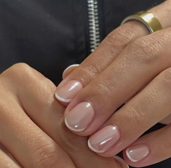 Short, rounded nails with a glossy nude base and delicate white French tips, perfect as inspiration for nail designs for short nail beds.