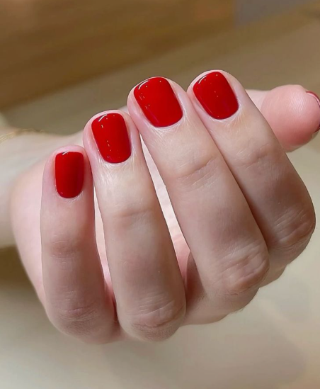 Short, squared-off nails with a vibrant, glossy red polish, making it a classic option for nail designs for short nail beds.